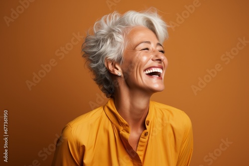Senior woman laughing heartily isolated on a burnt sienna gradient background 