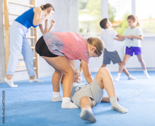 Kids in sportswear exercising self-protection techniques in pair during class at gym