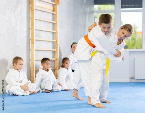 Young boys and girls athletes in white kimonos practice Brazilian jiu Jitsu Aikido Wing chun wrestling. Training at Academy of Martial Arts martial arts hand-to-hand combat.