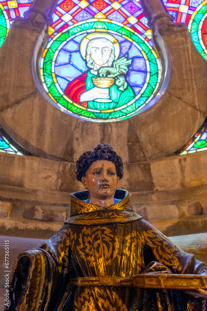 statue representing a saint in front of the Gothic rose window inside the Lisbon Cathedral