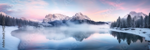 Panoramic view of beautiful lake at sunrise with foggy Winter forest mountain covered by heavy snow and ice. Winter seasonal concept.