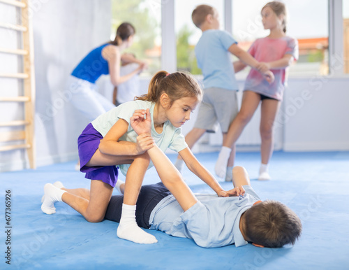 Young children, boy and girl, working in pair mastering new self-defense moves at gym