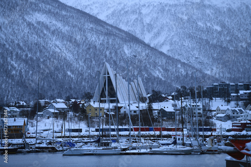 Early morning in a harbor at Tromsø with Arctic Cathedral and fjords on its background in the winter. North Norway