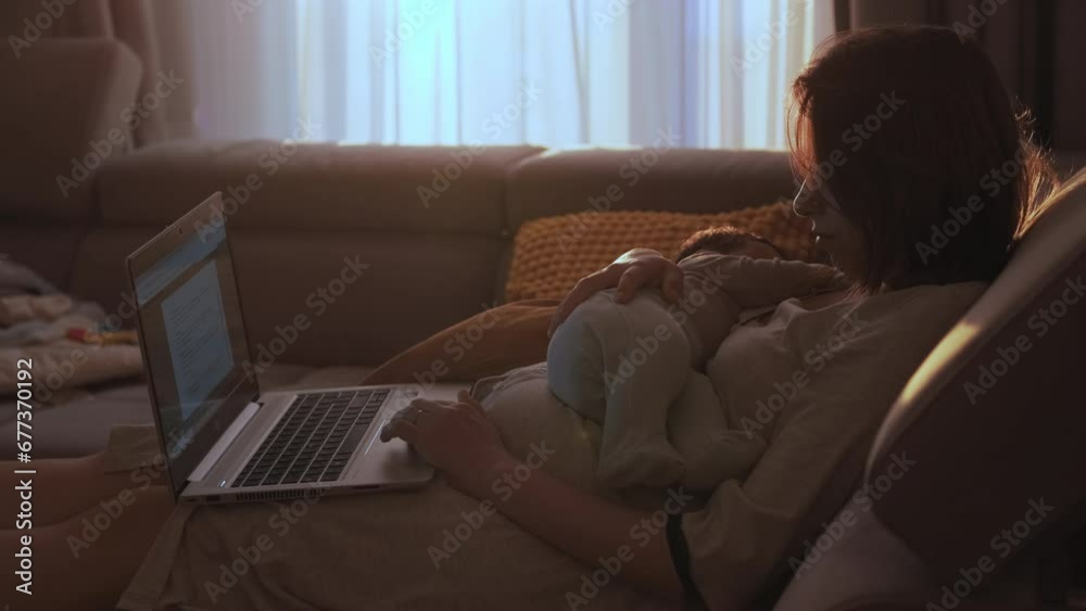 Caring mother works from home via computer holding and soothing newborn child. Female freelancer lies on couch in bedroom reviewing documents Caring mother works from home via computer holding and soothing newborn child. Female freelancer lies on couch in bedroom reviewing documents