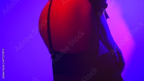 Sexy seductive lady in beautiful black lingerie striptease dancing, wearing stockings with suspenders. Beauty woman in colorful neon lights erotic girl fashion. Sexy buttocks. Slow motion