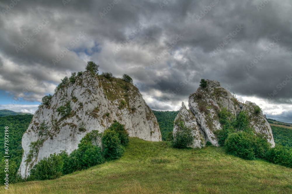 A cluster of massive boulders rests atop a vibrant, verdant hill