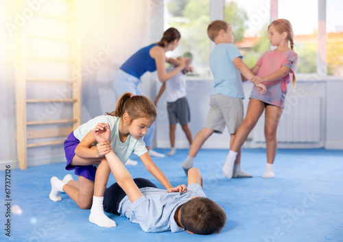 Kids practice grabbing their opponent's arms and taking them down in controlled manner.