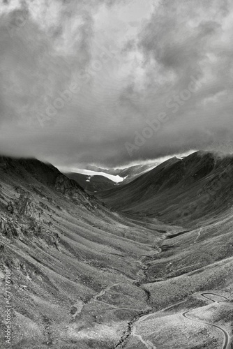 Vertical dark drone shot of rocky hills of Khardung la in Ladakh, India under cloudy sky photo