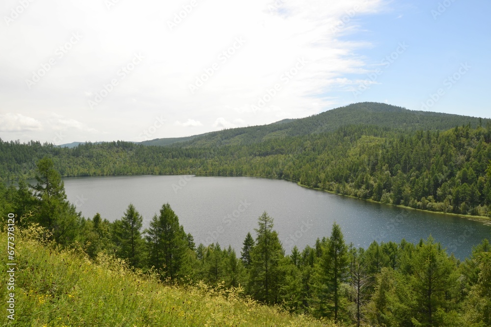 Landscape of a lake surrounded by hill and forests on a cloudy day Landscape of a lake surrounded by hill and forests on a cloudy day