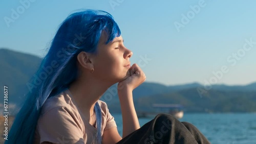 Colorful girl feel the breeze. A nice colorful girl sits on the beach and feel the warm breeze on her face against tropical bay. photo