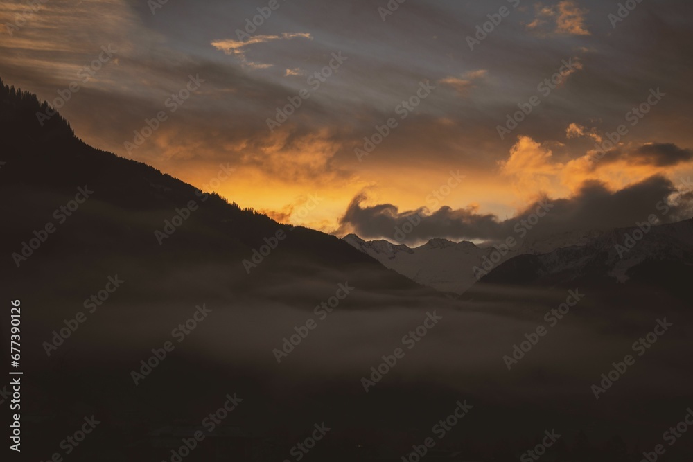 Breathtaking view of fog above a beautiful mountains during a mesmerizing sunset