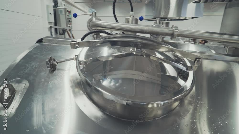 Close-up of a stainless steel tank used for milk processing at the factory. Stainless steel tank with huge amounts of dairy product inside. Stainless steel tank for milk pasteurization at dairy plant. Close-up of a stainless steel tank used for milk processing at the factory. Stainless steel tank with huge amounts of dairy product inside. Stainless steel tank for milk pasteurization at dairy plant.