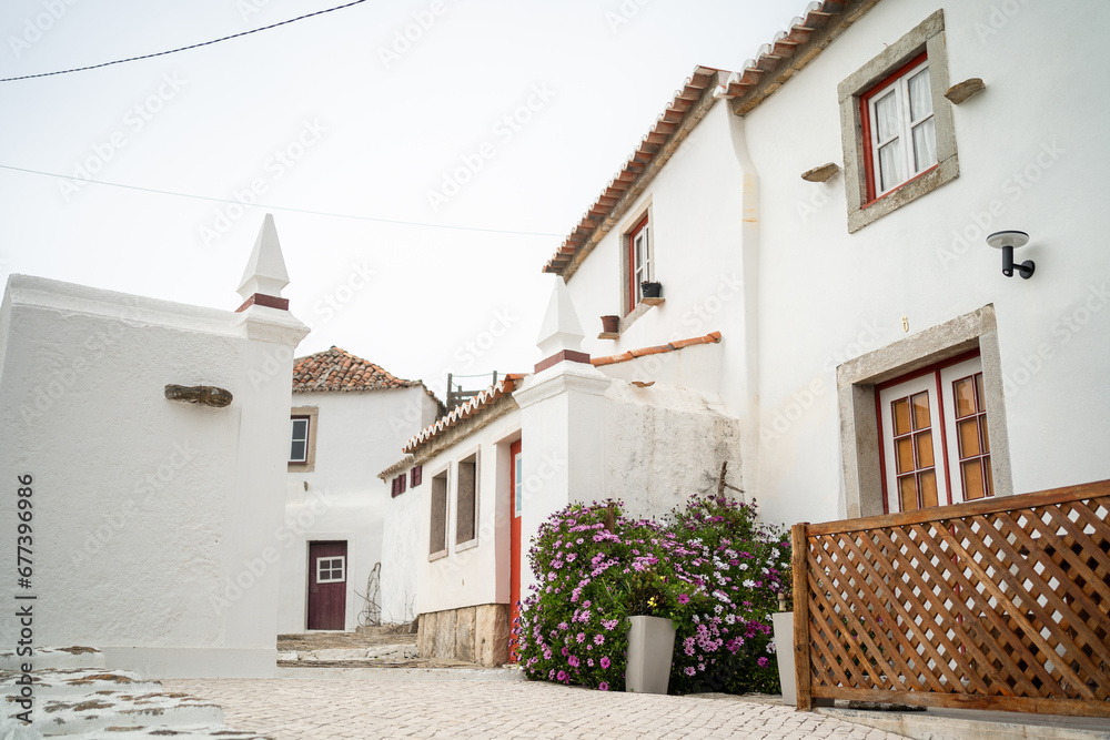 Typical streets in Portugal surrounded by white two-storey houses. Small Portugal city Azenhas do Mar with flower fence and beautiful houses. Shot passing by white big house on narrow street