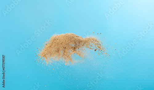 Big size Sand flying scatter, Golden grain wave explode. Abstract cloud fly. Yellow colored sand splash throwing in Air. Blue sky background Isolated, throwing freeze stop motion