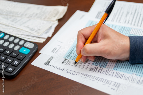 A man organizing individual income tax return form 1040 and receipts. Blurred background. Tax time.Tax concept. Close-up. photo