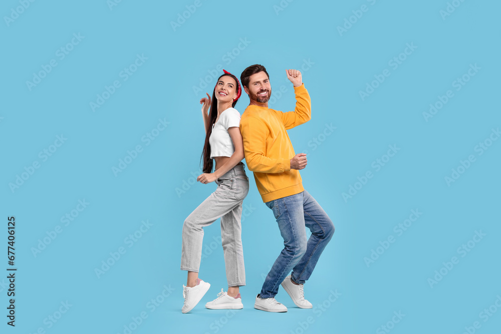 Happy couple dancing together on light blue background Happy couple dancing together on light blue background