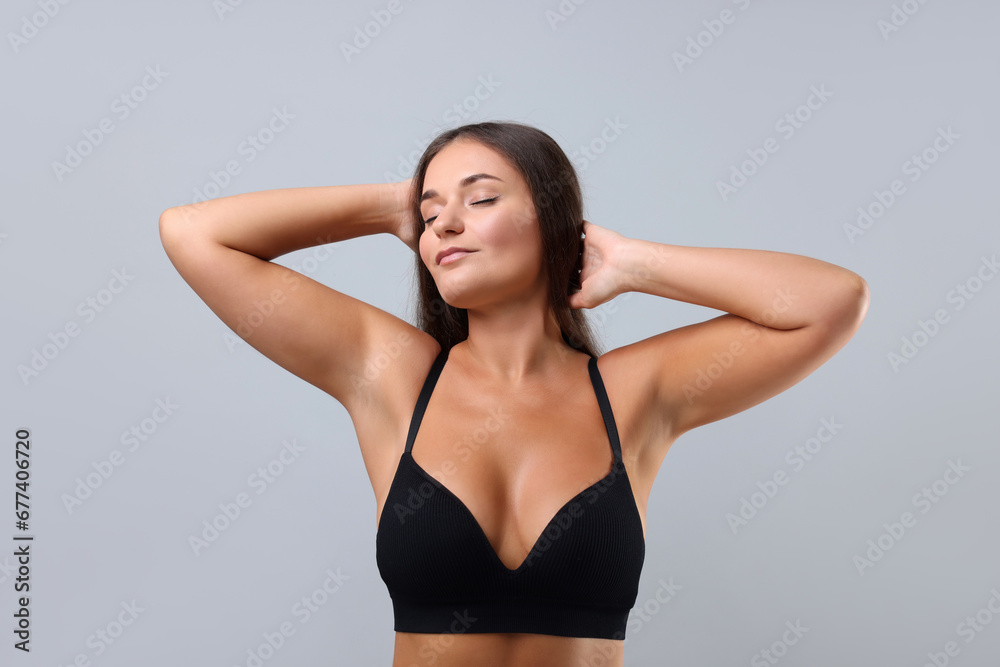 Portrait of young woman with beautiful breast on light grey background