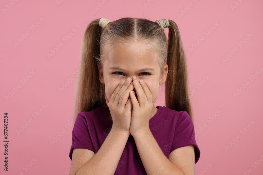 Embarrassed little girl covering her mouth with hands on pink background Embarrassed little girl covering her mouth with hands on pink background