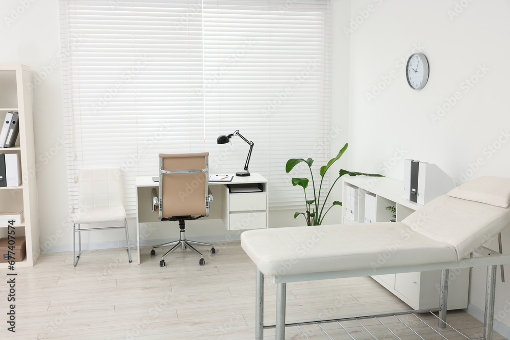 Modern medical office with doctor's workplace and examination table in clinic