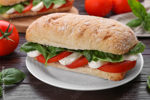 Delicious Caprese sandwich with mozzarella, tomatoes and basil on wooden table, closeup