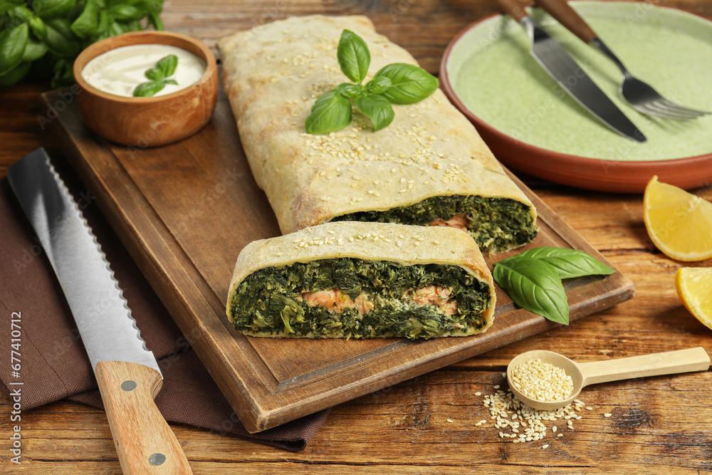 Cut tasty strudel with salmon, spinach, basil and sauce on wooden table Cut tasty strudel with salmon, spinach, basil and sauce on wooden table