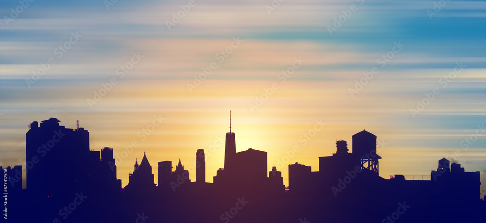 New York City downtown skyline buildings silhouetted against the colorful sky with the light of sunset in the background