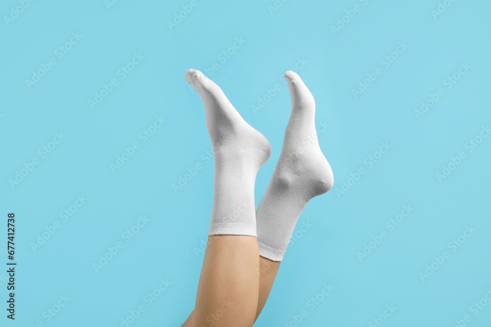 Woman in stylish white socks on light blue background, closeup Woman in stylish white socks on light blue background, closeup