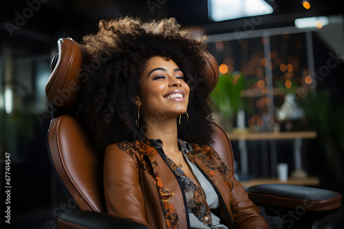 A happy young African American woman sits in her chair, smiling,