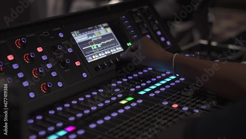 Close up of a sound guy mixing audio levels at a live event indoors on the board photo