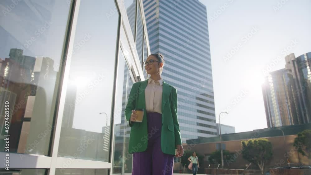 Smiling attractive business girl enjoying sunshine day. Career people shot 4K. Successful young beautiful woman coffee cup walking at modern business buildings on urban background at sunset Smiling attractive business girl enjoying sunshine day. Career people shot 4K. Successful young beautiful woman coffee cup walking at modern business buildings on urban background at sunset