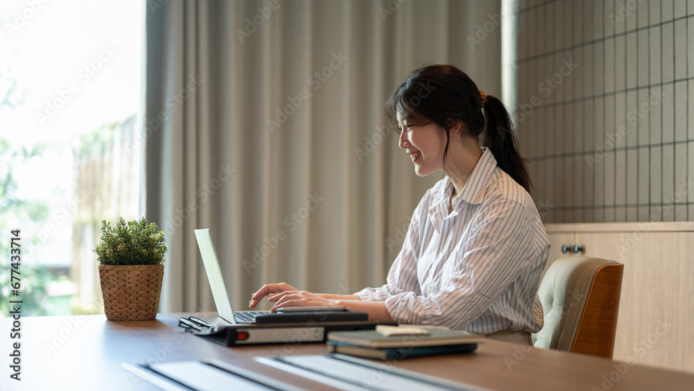 A beautiful Asian businesswoman working on her laptop at a meeting table in a meeting room alone. A beautiful Asian businesswoman working on her laptop at a meeting table in a meeting room alone.