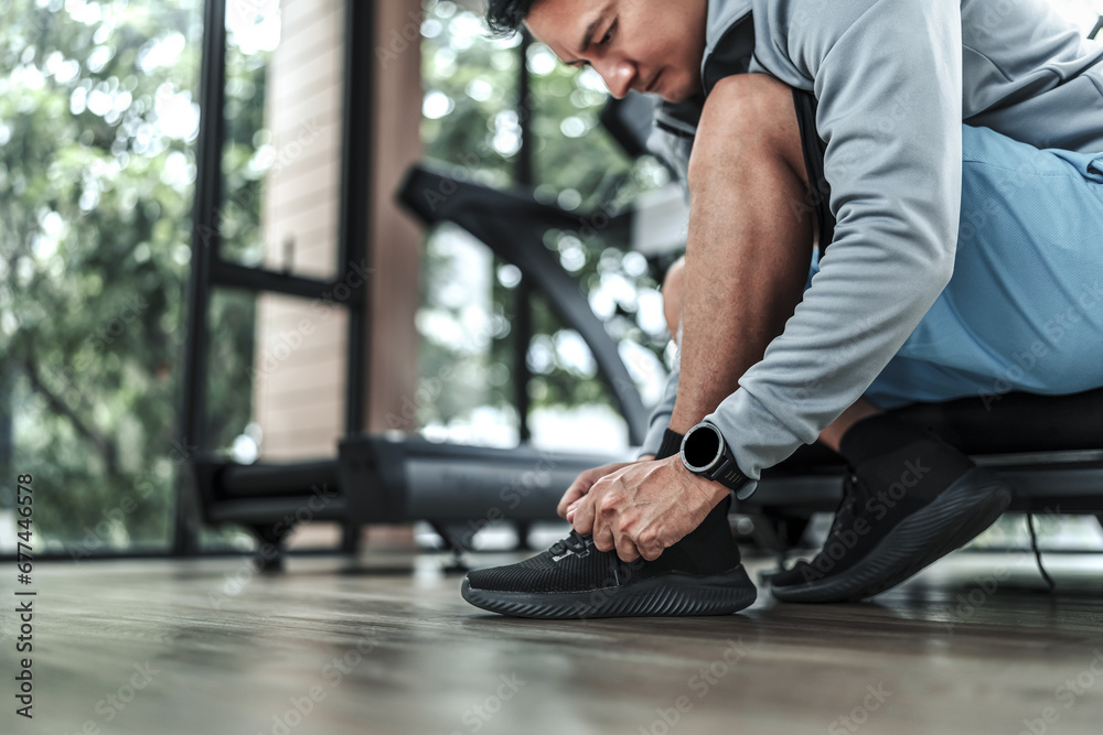 man's hands tying shoe laces in the gym.  Fitness, workout and traning at concept.