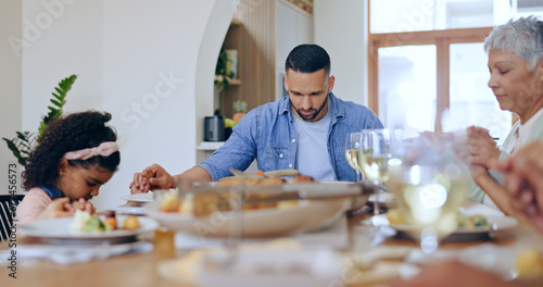 Christian, family and praying at dinner in home with gratitude, thanks and praise for God. People, pray and together giving spiritual respect or grace at lunch, table and holding hands in dining room