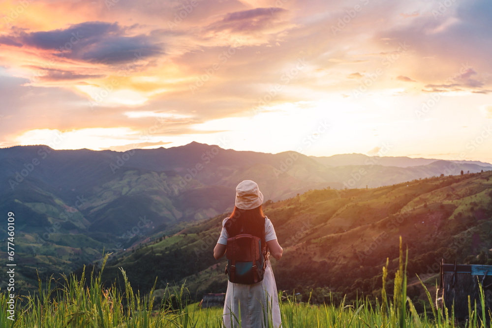 Happy young woman traveler relaxing and looking at the beautiful sunrise on the top of mountains, Travel lifestyle concept