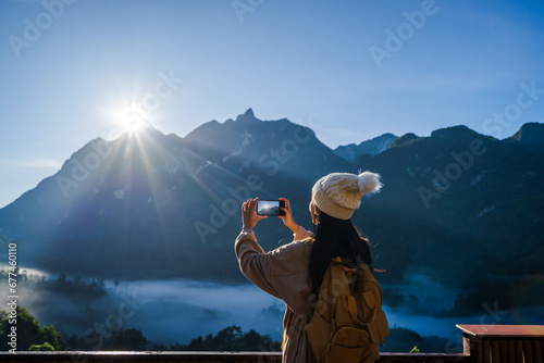 Young woman traveler taking a beautiful landscape at sunrise over the mountains, Travel lifestyle concept photo