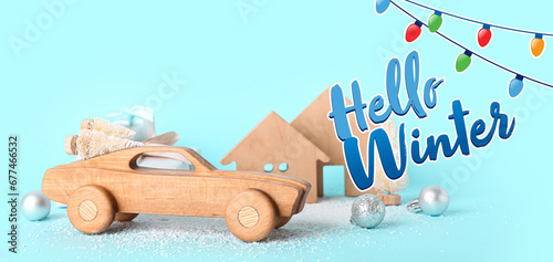 Composition with wooden car and Christmas decorations on light blue background. Hello winter