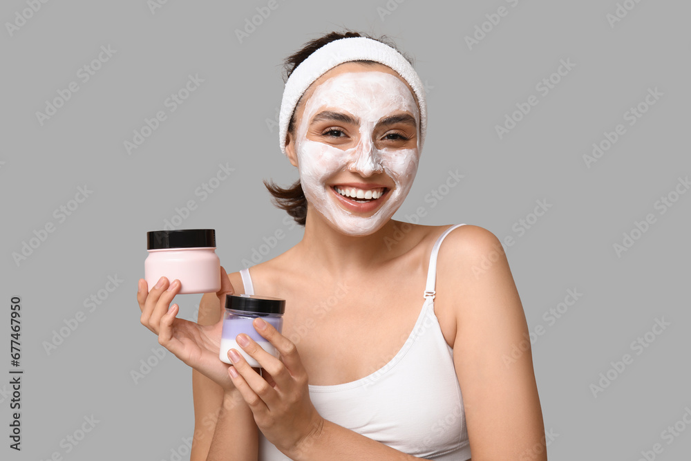 Young woman with jars of cream on light background Young woman with jars of cream on light background