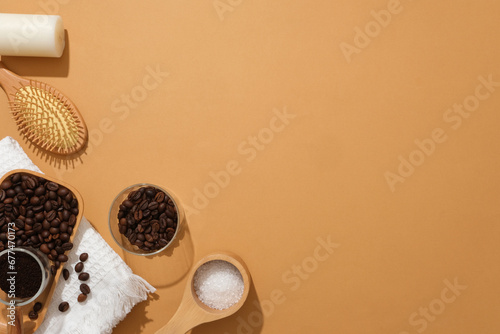 Wooden tray containing coffee beans, coffee powder and bath salt, decorated with candle and comb on orange background. Empty space for presentation product and copy space