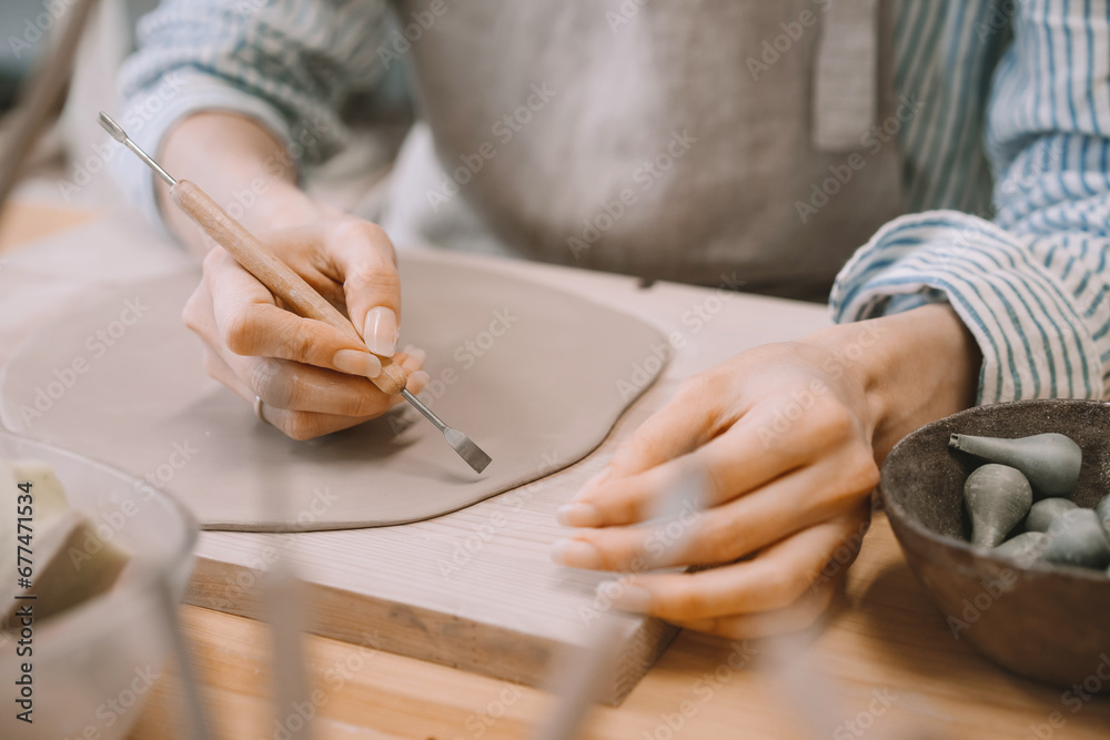 Obraz premium Female hands working with clay makes ceramic tableware on pottery workshop.