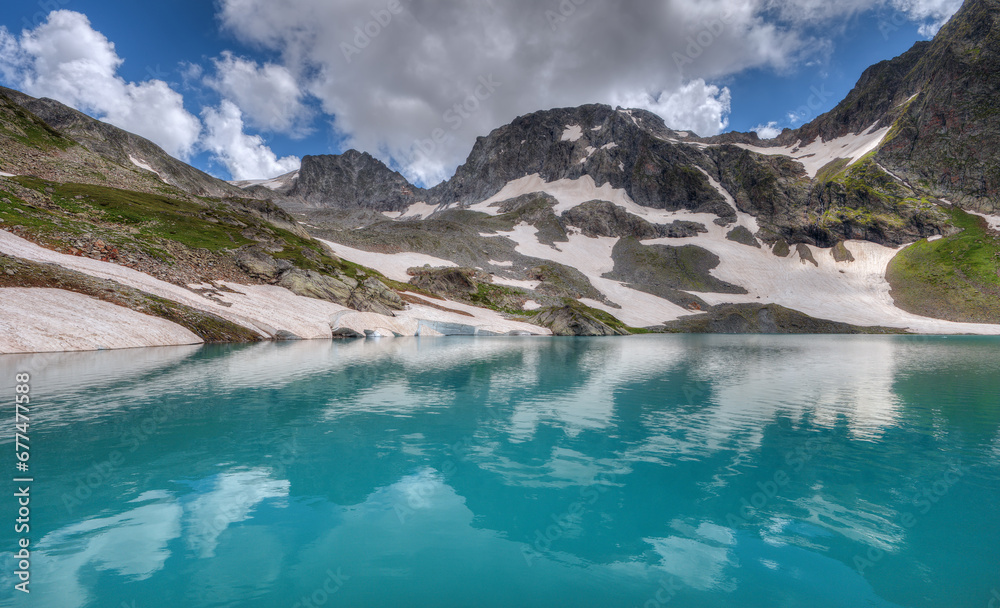 Beautiful lake in a mountain valley. Mountains with glaciers. Imertinskoye Lake in the Caucasus Nature Reserve.