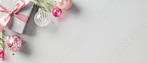 Elegant Christmas composition with festive present, pink ribbon, and glittering ornaments. Modern holiday design in grey and pink tones. Luxury Xmas banner design. © photoguns
