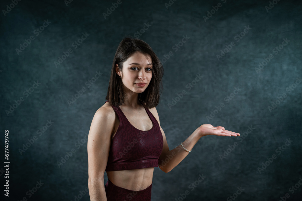 Young slim female fitness trainer wearing sports bra posign at studio isolated on black Young slim female fitness trainer wearing sports bra posign at studio isolated on black