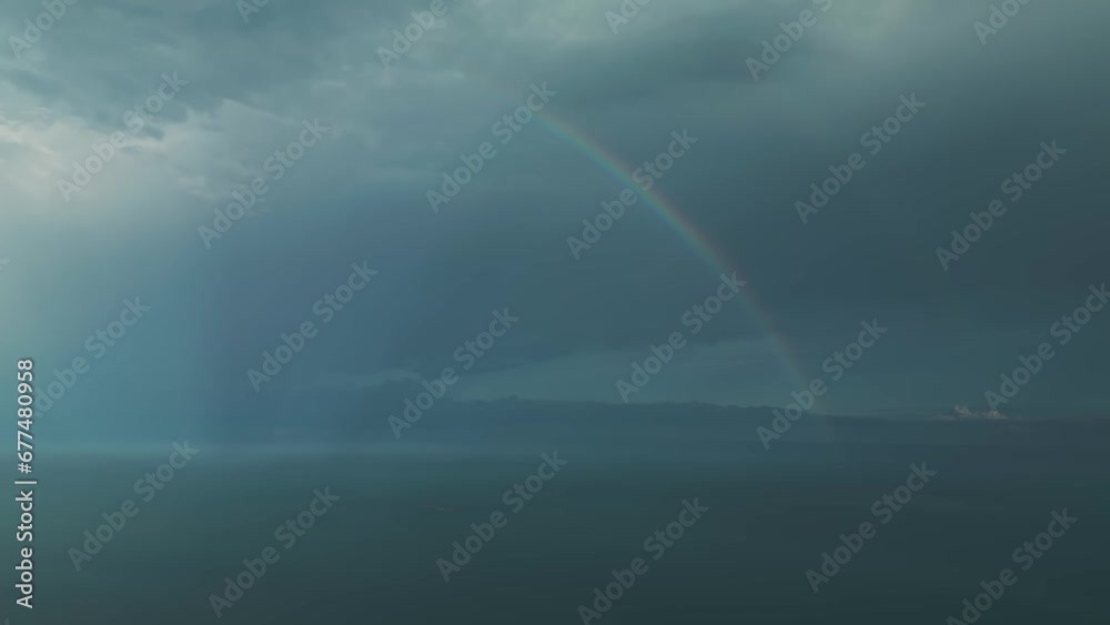 Aerial view of rain clouds and a rainbow in the sky above the sea Aerial view of rain clouds and a rainbow in the sky above the sea