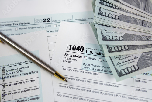 Income tax return 1040 forms with blue pen and us dollar bills at office desk