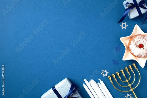 Hanukkah celebration photo with festive menorah, sufganiyot, candles, and gift boxes on a blue background. Perfect for holiday card, banner, or invitation. Jewish culture and tradition composition