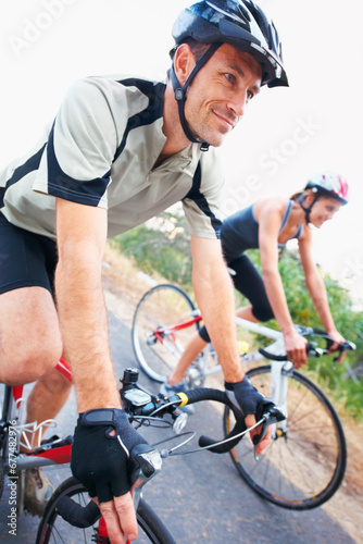 Happy, couple and cycling on road in nature for cardio, fitness and training on bicycle together. Outdoor, people and exercise on bike for fun, workout and travel in countryside adventure or journey