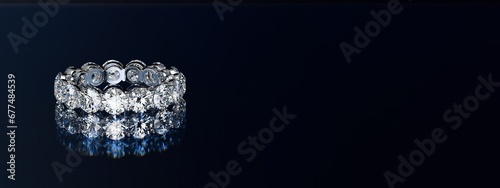 Eternity diamond ring on black glossy background. Wide image.