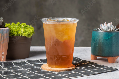 Meng Po tea served in disposable glass isolated on wooden board side view of taiwanese ice drink photo