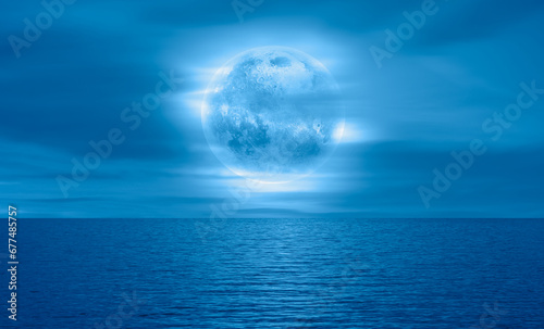 Night sky with blue moon in the clouds over the calm blue sea "Elements of this image furnished by NASA"