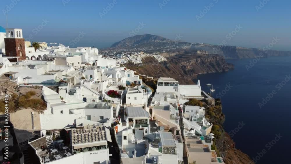 Oia village cliffside houses and hotels in Santorini,  Greece, Cinematic aerial view